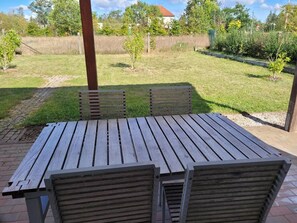 An outdoor wooden table with benches, surrounded by a grassy area and trees. - Apartment with Garden, Terrace, Private Garden & Wi-Fi in Milmersdorf (Milmersdorf)