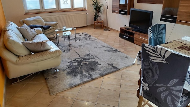 A living room with a sofa, a coffee table, a TV, and a plant.