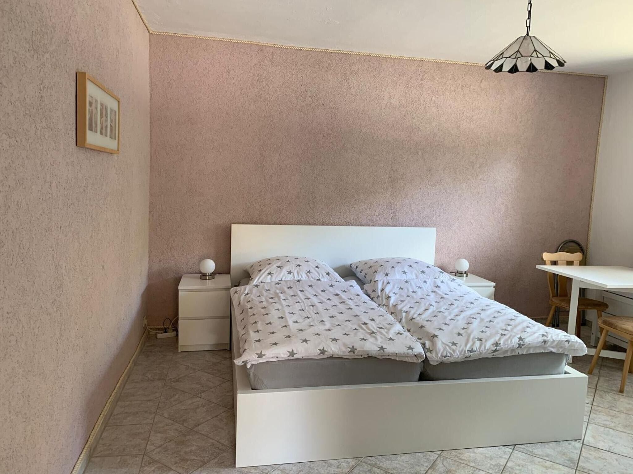 Une chambre à coucher avec un lit, des tables de chevet, un bureau et une chaise.
