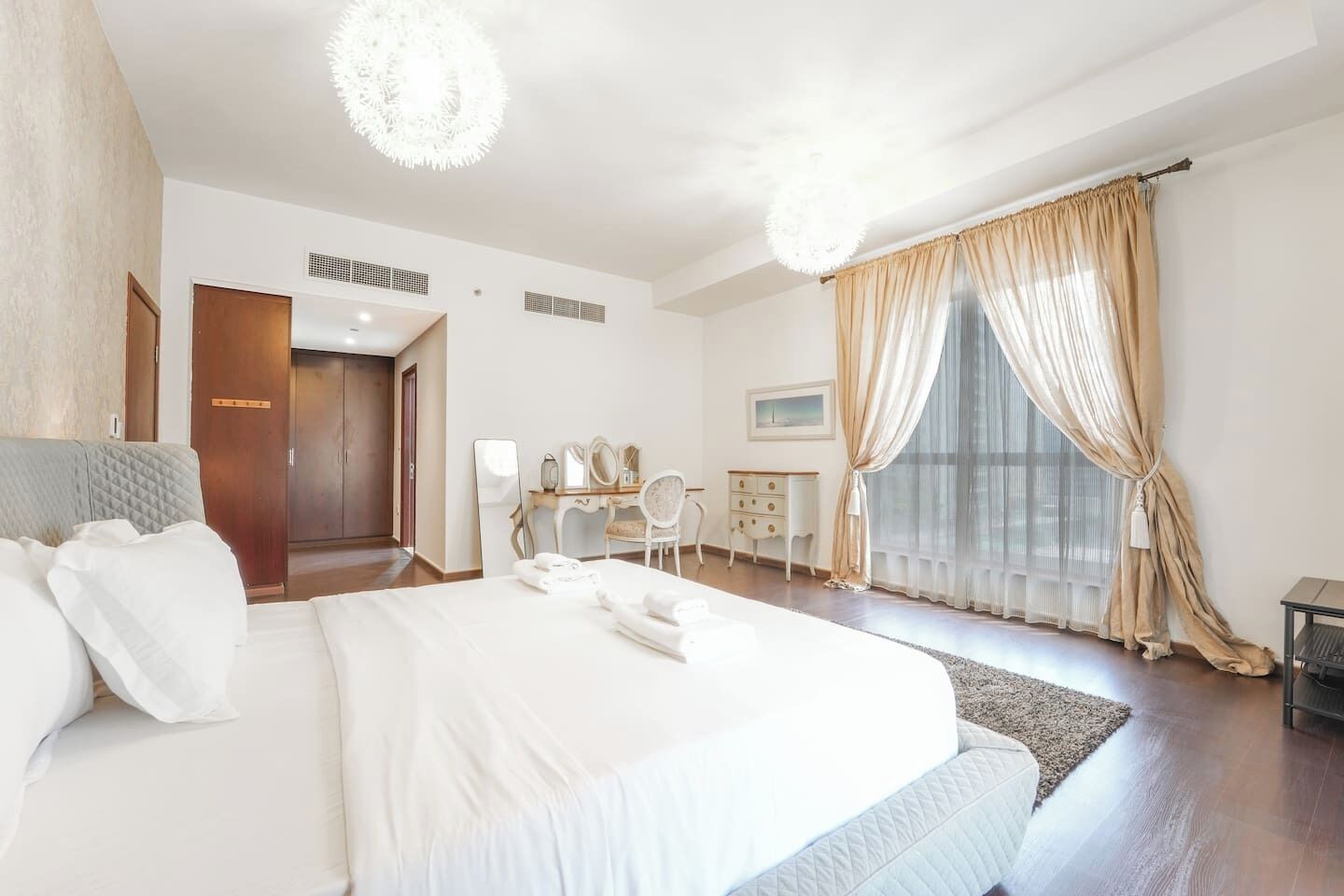 Ein Hotelzimmer mit einem großen Bett, einem Schreibtisch, einem Sessel und einem Kleiderschrank.
