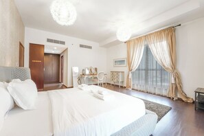A hotel room with a large bed, a desk, a chair, and a wardrobe. - Spacious 3BR in Amwaj | Steps from the Beach (Dubai)