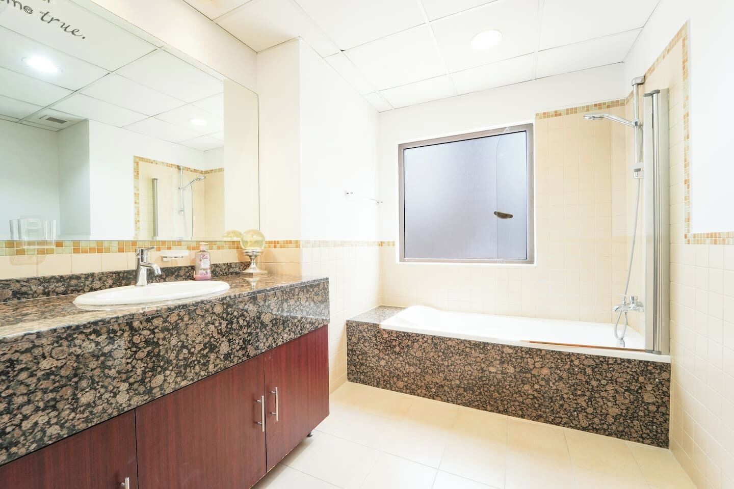 Une salle de bain avec un comptoir en granit, un lavabo, un miroir, une douche et des toilettes.