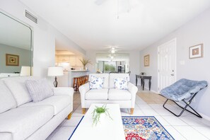 A modern living room with a sofa, a coffee table with a plant, and a blue patterned rug. - Romar Village 312  Family-Friendly Beach Retreat (Orange Beach)
