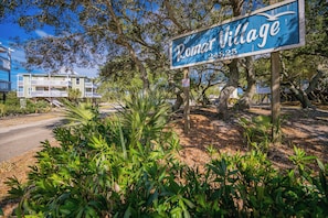 Schild für 'Romar Village' mit einer Straßenansicht im Hintergrund.