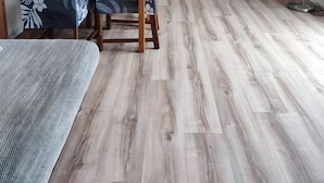 Cozinha moderna com armários brancos, mesa de jantar de madeira e cadeiras com padrão de folha.