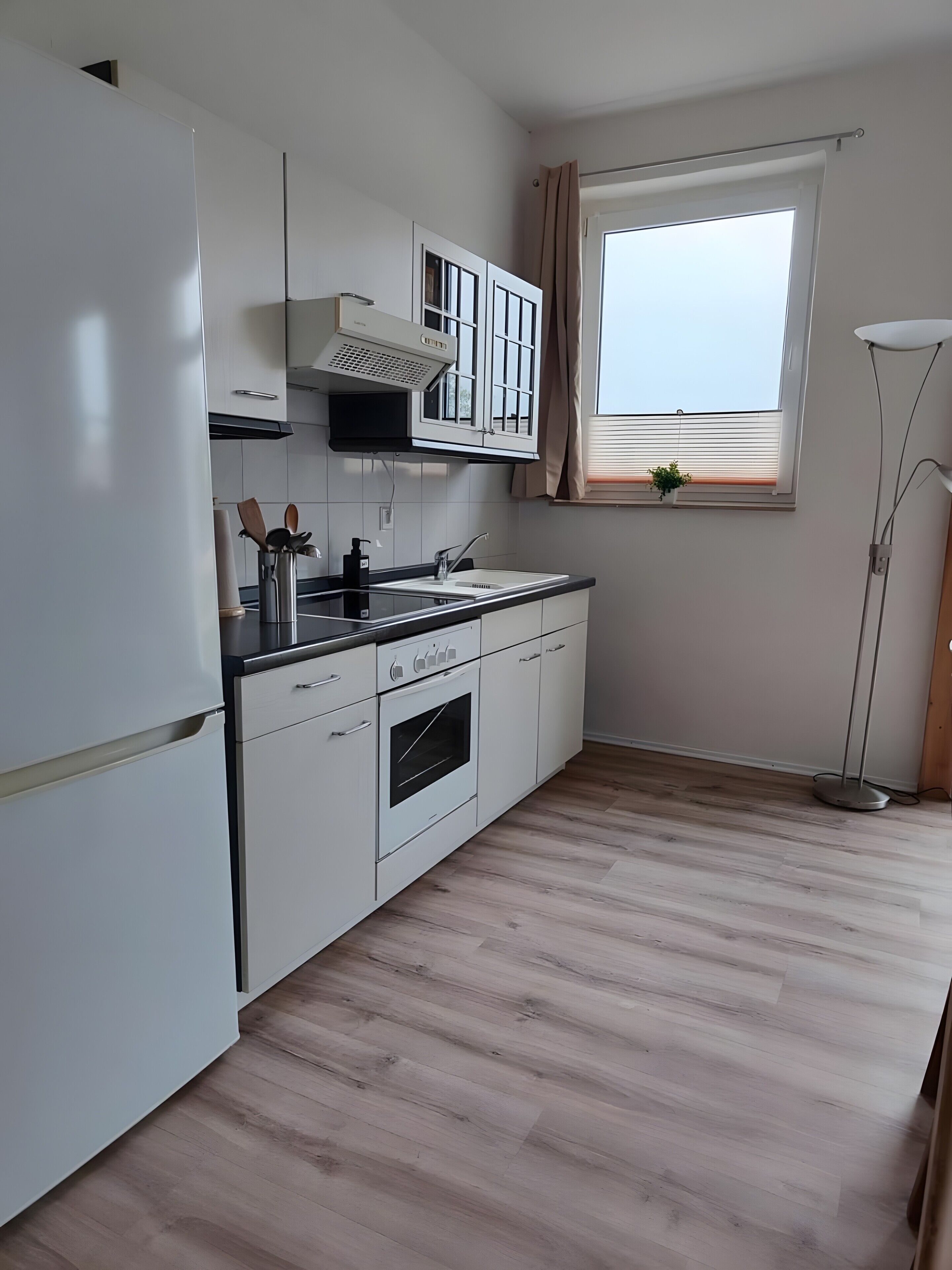 A modern kitchen with white cabinetry, a built-in oven, and a window with a view.