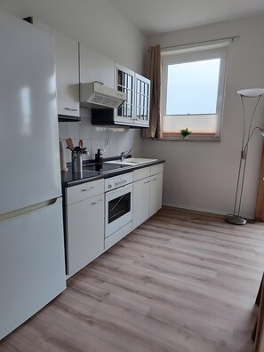 A modern kitchen with white cabinetry, a built-in oven, and a window with a view.