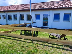 A building with a red-tiled roof, multiple windows, and a wooden fence in the foreground.