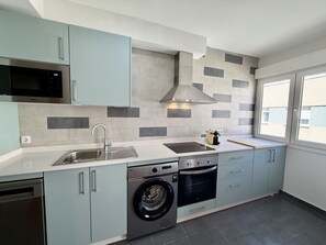 A modern kitchen with a built-in washing machine, a microwave, and a stove. - Dragos Suites 201 (Arrecife)