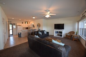 A modern living room with a dark leather sofa, a flat-screen TV, and a ceiling fan. - In the Middle of it All -2 Pools,Grill,Fishing,Boat Launch,Boat rental next door (Osage Beach)