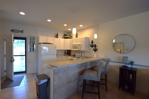 A modern kitchen with white cabinetry, a central island, and pendant lighting. - In the Middle of it All -2 Pools,Grill,Fishing,Boat Launch,Boat rental next door (Osage Beach)