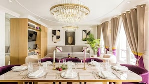 Uma área de refeições com um candelabro, um sofá e uma mesa posta para uma refeição.