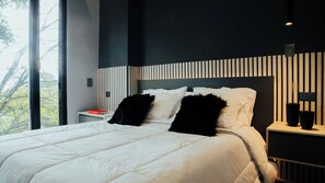 A modern bedroom with a large bed, a nightstand, and a view of trees. - Top Provenza Penthouse 3-bedroom apartment w/ AC, Elevator, Fast Wifi, Parking (Medellín)