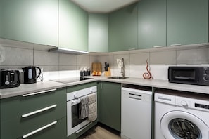 A compact kitchen with a dishwasher, oven, microwave, and a sink. - Karazo Ltd - 2 bedroom home in Croydon (Croydon)