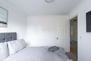Quarto com cama, porta e corredor.