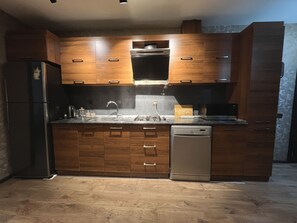 A modern kitchen with wooden cabinets, stainless steel appliances, and a dishwasher. - Spacious 2BR near Winter Park - Sleeps 5 (Baku)