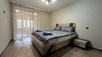 Ein Schlafzimmer mit einem Bett, einem Nachttisch, einem Deckenventilator und einem Fenster mit Vorhängen.