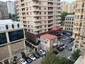 A multi-story residential building with balconies, a parking area, and a bank with a red awning. - Spacious 2BR near Winter Park - Sleeps 5 (Baku)