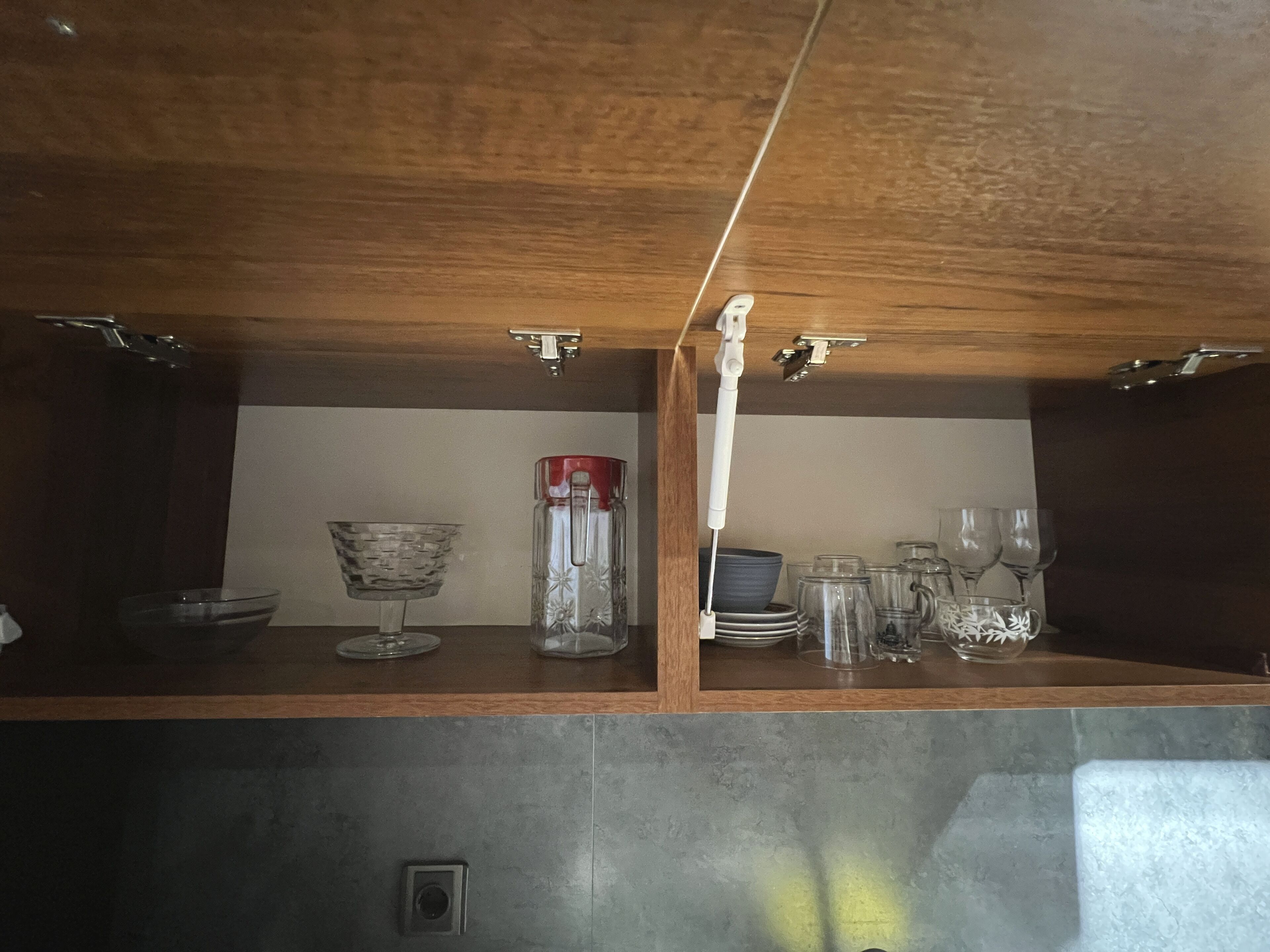 A kitchen with wooden cabinets, a countertop, and various glassware and dishes.