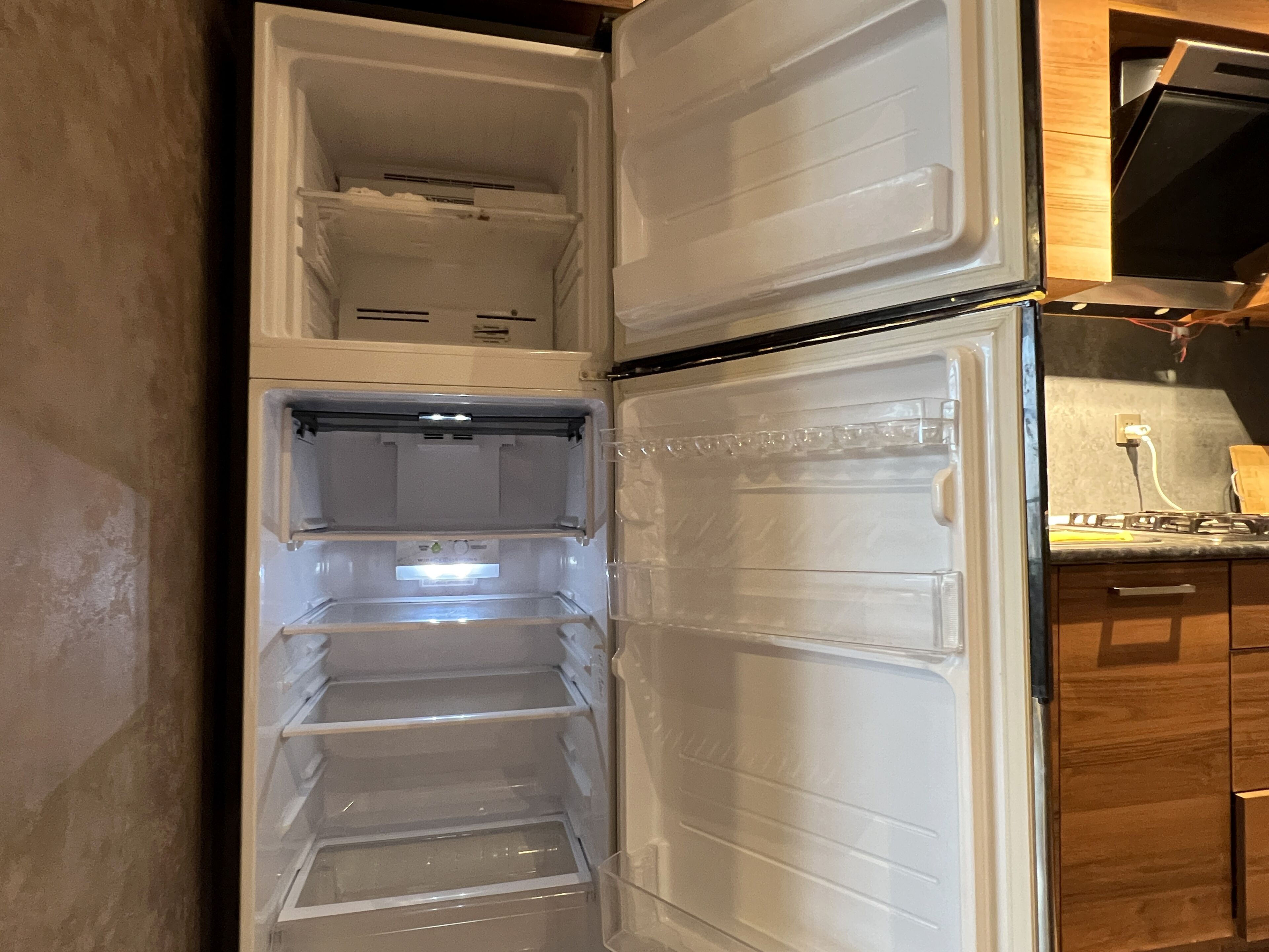 Un refrigerador abierto con varios estantes y un compartimento congelador.