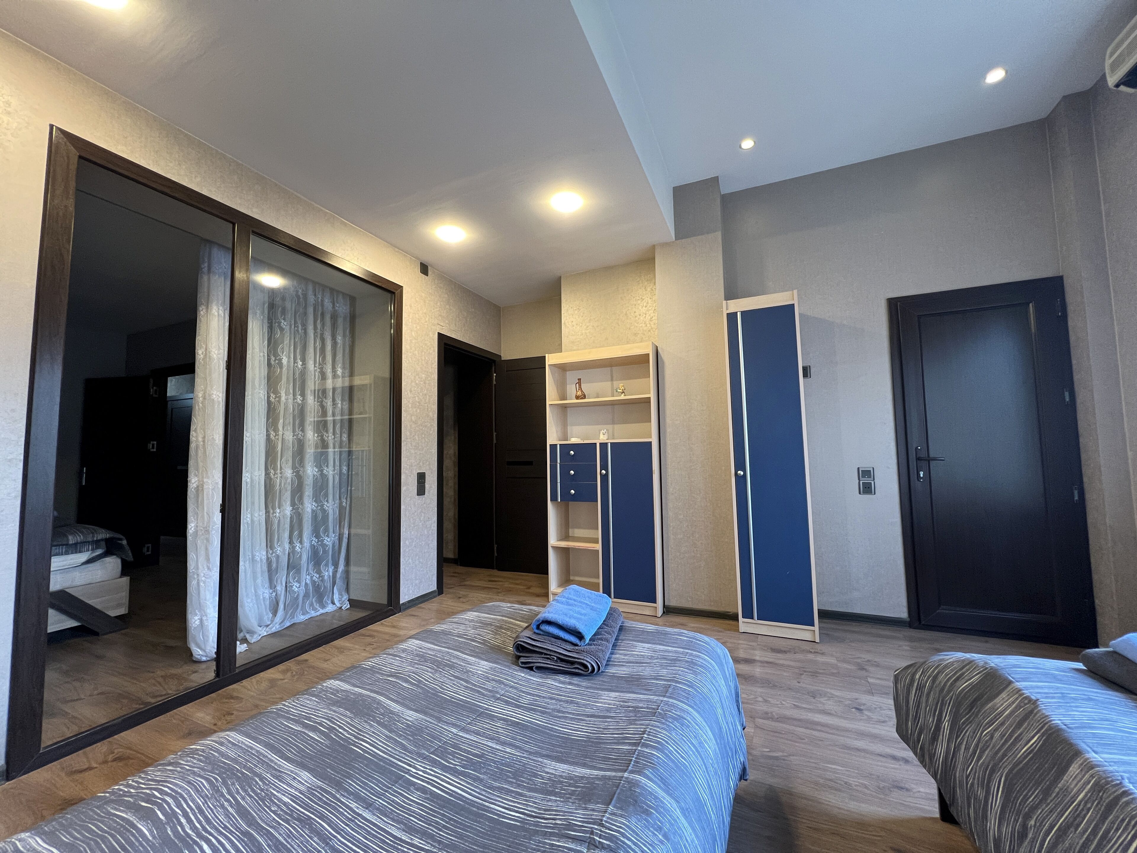Een moderne hotelkamer met een groot bed, een kledingkast, een bureau en een schuifdeur naar een balkon.