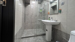 Un bany modern amb dutxa envidrada, un lavabo blanc i un mirall.