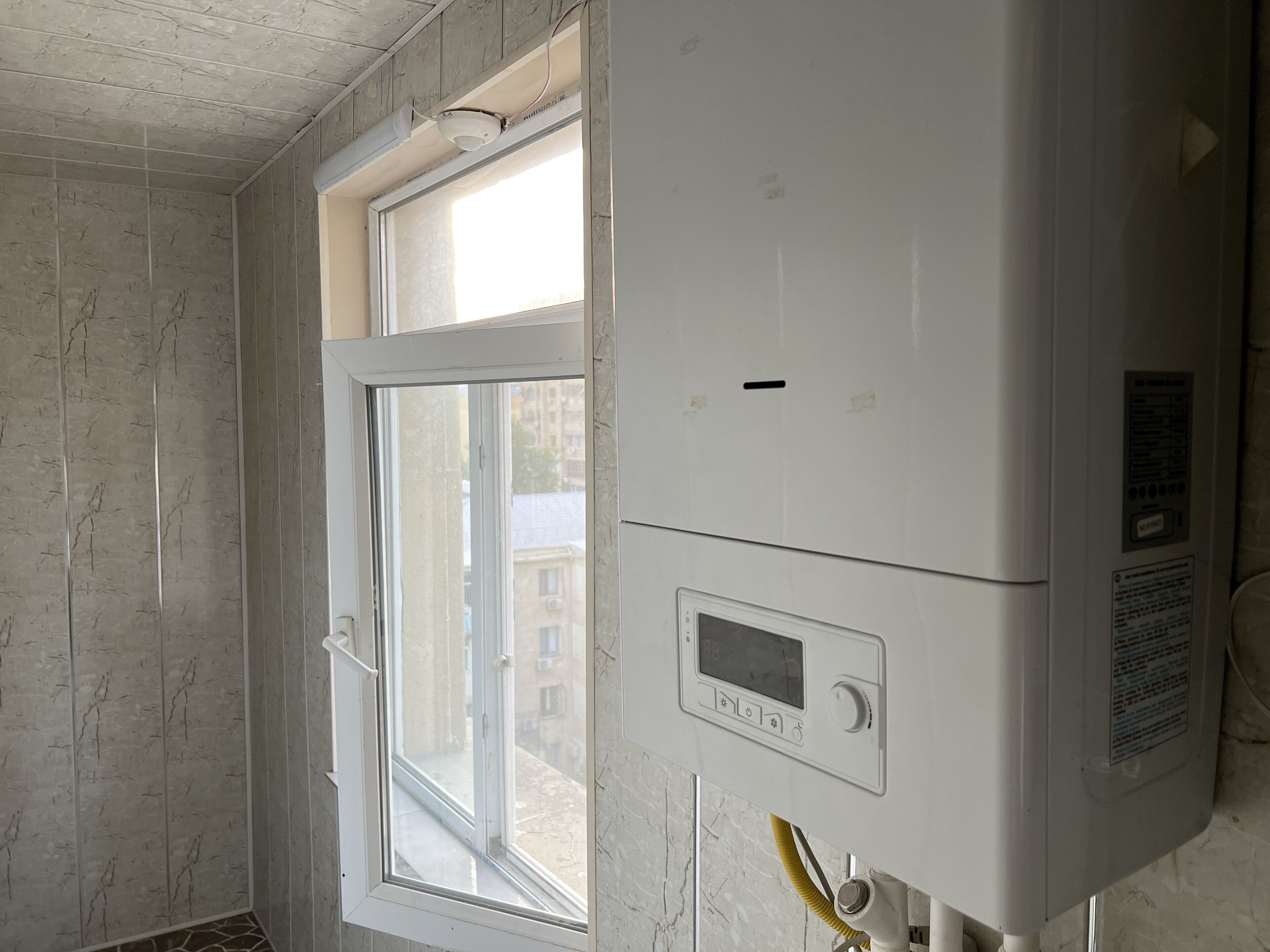 Une pièce avec une fenêtre, un mur blanc et un thermostat.