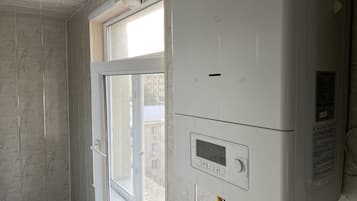 Une pièce avec une fenêtre, un mur blanc et un thermostat.