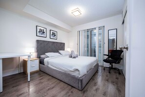 A modern bedroom with a bed, bedside tables, a desk, and a chair. - Modern 3BR Retreat, Bright & City-View (Toronto)