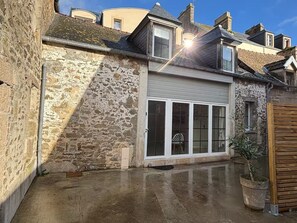 A stone building with a garage door, a potted plant, and a clear sky. - Vrbo Property (Saint-Vaast-la-Hougue)