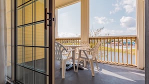 Ein Balkon mit Tisch und Stühlen, Blick auf ein Gewässer sowie ein Gebäude mit gelber Fassade.