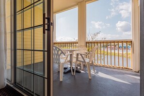 Ein Balkon mit Tisch und Stühlen, Blick auf ein Gewässer sowie ein Gebäude mit gelber Fassade.
