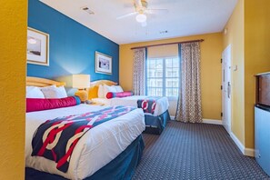 Ein Hotelzimmer mit zwei Betten, einem Deckenventilator, einem Fenster mit Vorhängen und einer Tür.