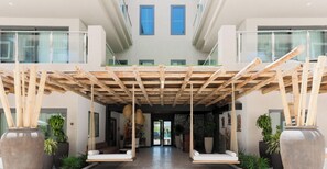 Un intérieur moderne avec une structure de plafond en bois, de grandes plantes en pot et un espace salon.