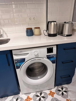 A kitchen with a washing machine, two jars, and two kettles on the counter. - Light and spacious flat in central Istanbul (Şişli)