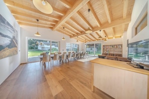 A spacious kitchen with wooden beams, large windows, and a dining area with wicker chairs. - Chalet Dumbria Dolomites - Exclusive for up to 17 people (Selva di Val Gardena)