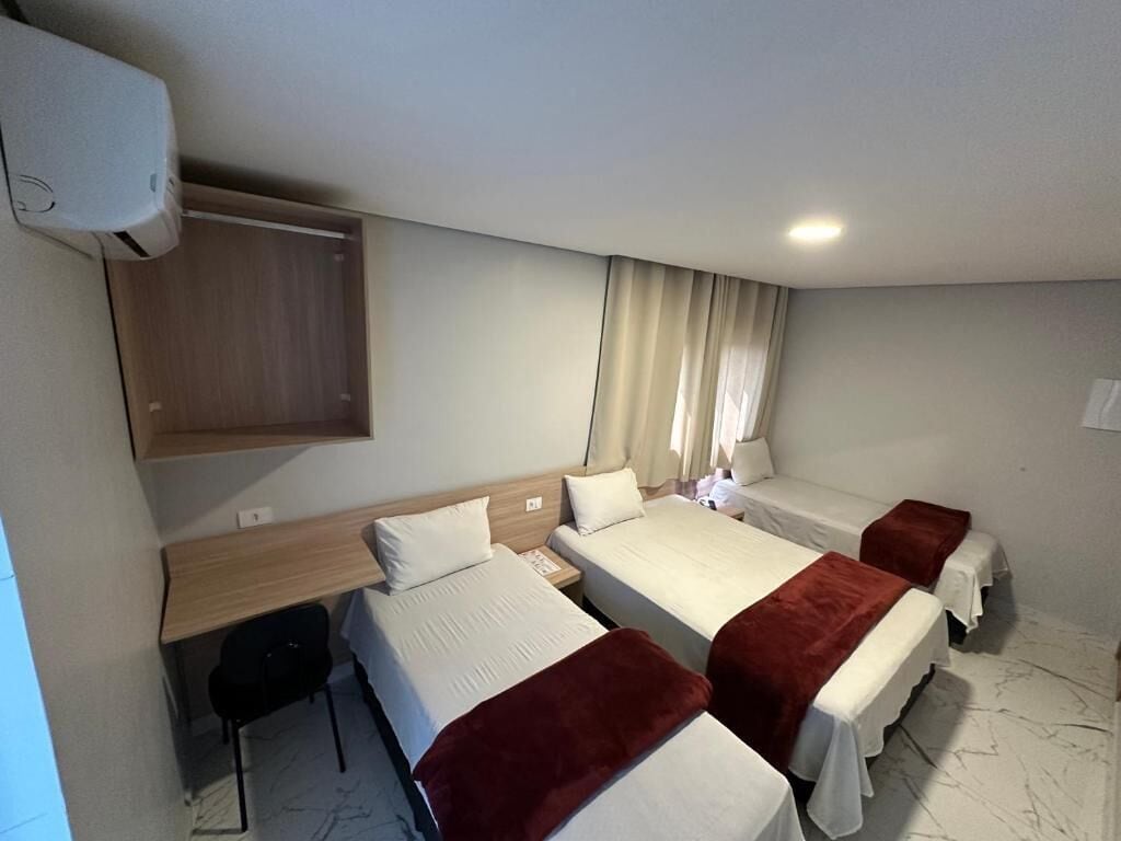 A hotel room with three beds, a desk, and a wardrobe.