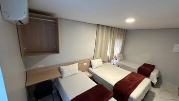 A hotel room with three beds, a desk, and a wardrobe.