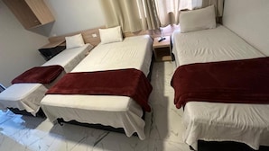 Una habitación con dos camas, una mesita de noche y un armario de madera.