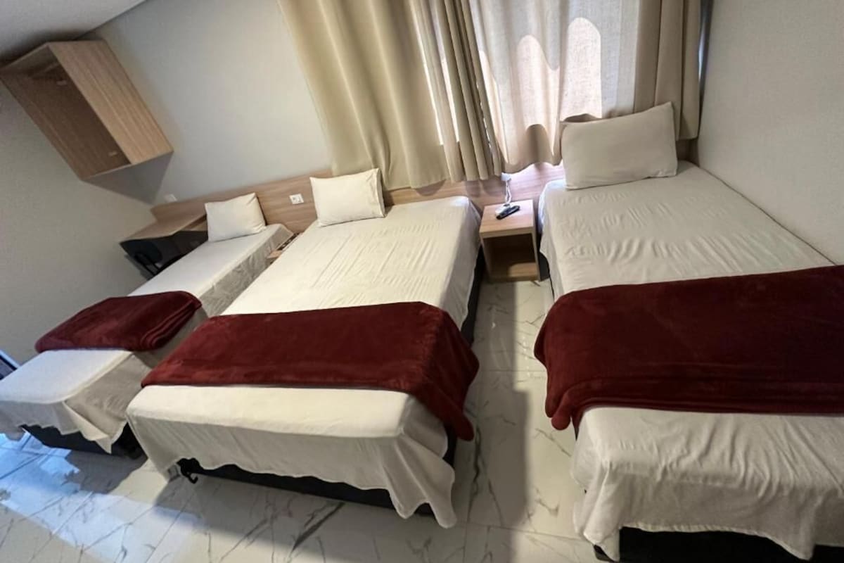 Una habitación con dos camas, una mesita de noche y un armario de madera.