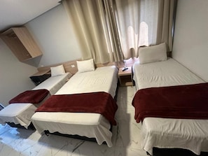 Una habitación con dos camas, una mesita de noche y un armario de madera.