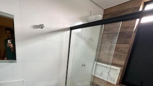 Un baño moderno con cabina de ducha de vidrio, inodoro blanco y piso de baldosas de mármol.