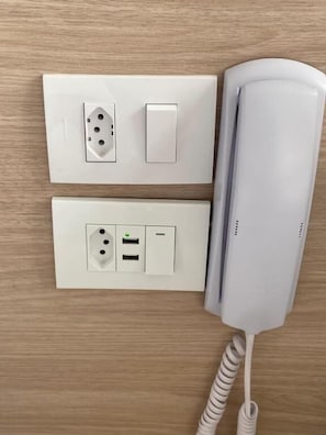 A wall-mounted telephone and two electrical outlets with a switch.