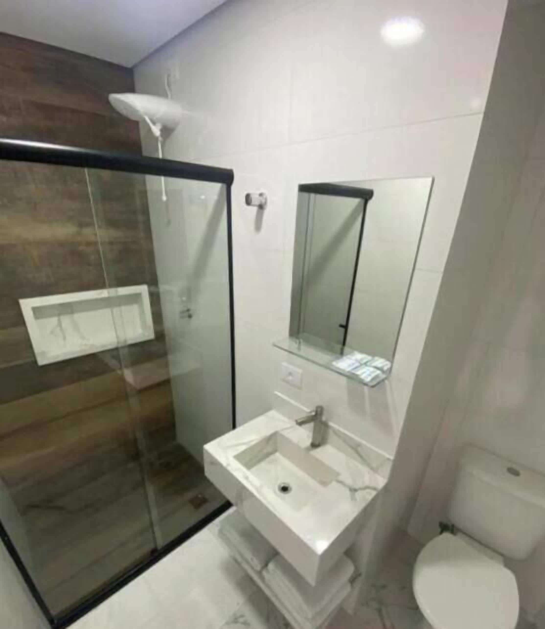 Ein modernes Badezimmer mit Duschkabine aus Glas, Waschbecken in Weiß und Toilette.
