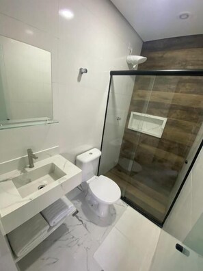 A modern bathroom with a glass-enclosed shower, a white sink, and a toilet.