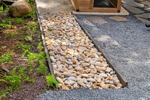 Un chemin de jardin bordé de gravier et un bac rectangulaire rempli de petits cailloux.