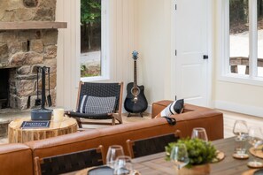 Un coin salon accueillant avec une cheminée en pierre, une guitare et une table dressée pour le repas.