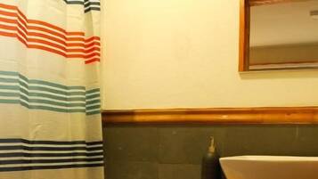 Une salle de bain avec un rideau de douche à rayures, des toilettes avec un rouleau de papier toilette et un lavabo avec un miroir au-dessus.