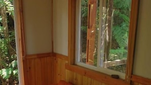 Ett rum med en väggpanel av trä, ett fönster med utsikt över grönområden och en soffa.