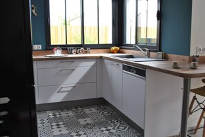 Eine Küche mit eingebautem Geschirrspüler, einer Spüle und einem Fenster mit Blick auf einen Holzzaun.